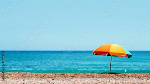 A vibrant beach umbrella stands out against the subtle shades of the sea and sky, a cheerful sentinel of sunny days and gentle breezes.