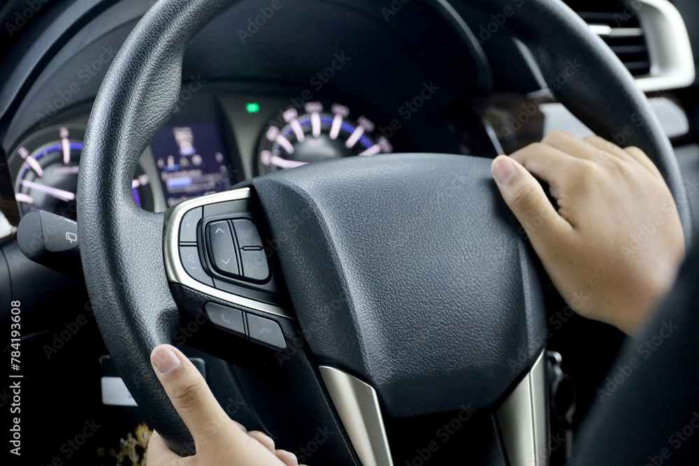 Driver's hands on the steering wheel inside of a car
