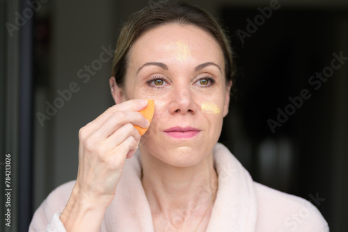 Blonde woman applying makeup with a sponge