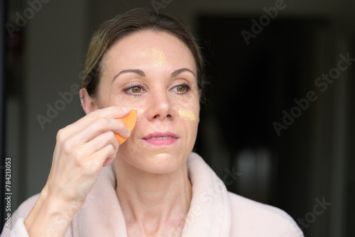 Blonde woman applying makeup with a sponge