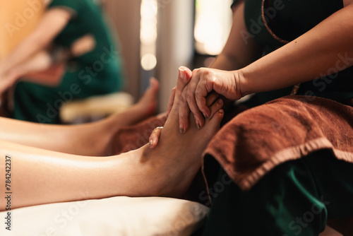 Selective focus on hand, Masseuse acupressure massage on feet of customer. Masseuse service foot massage to woman customer. Relaxation foot massage in cosmetology spa centre. photo