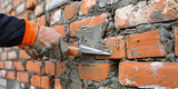 Masonry works A person working in the construction of a building Bricklayer laying bricks on mortar on new residential house construction 