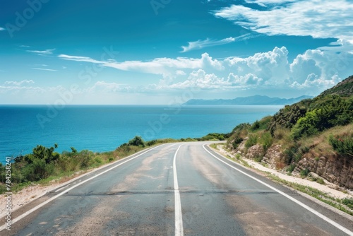 Coastal road leading towards the horizon with clear blue skies and ocean beside.