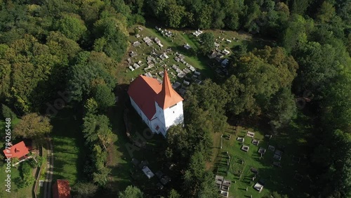 Aerial view of a whitewashed church and graveyard. Drone shot of a medieval landmark in Bikfalva, Bicfalau, Szeklerland, Romania photo