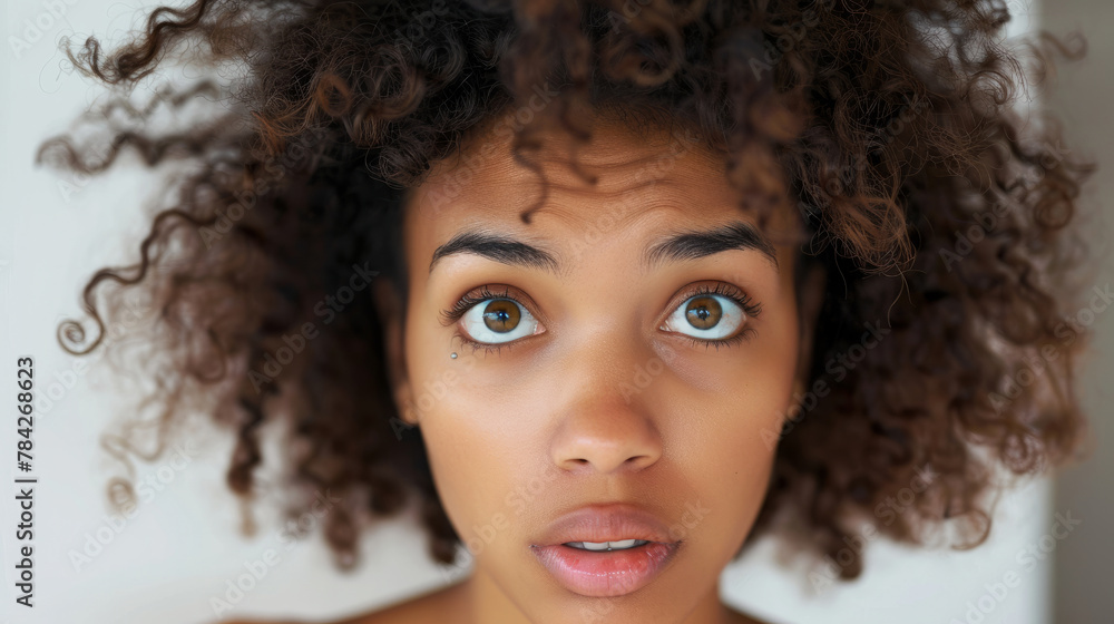 A woman with curly hair and a surprised expression. The woman is wearing a shirt. Concept of surprise and curiosity. a picture of an african american woman