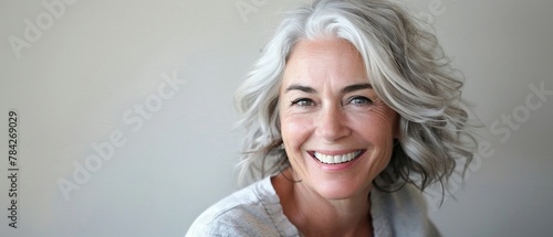 A radiant mature woman with silver hair exudes confidence and joy with her bright photo