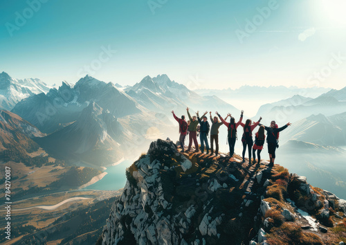 A group of friends are celebrating on the top of an alpine mountain, overlooking vast landscapes and lakes at sunrise photo