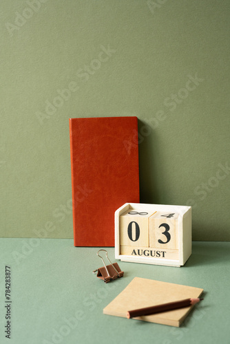 Workspace diary note, calendar, notepad, clip, pencil on green desk. khaki wall background
