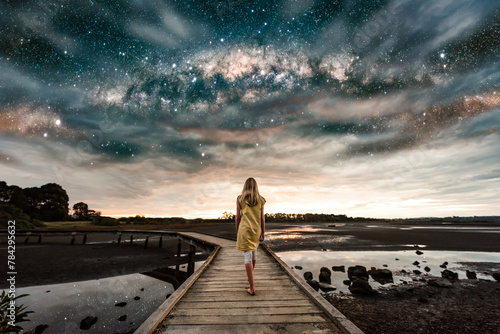 Girl walking on boardwalk under the Milky Way stars photo