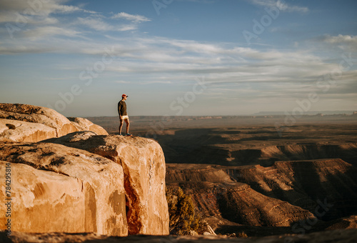 Man in shorts stands at edge of cliff overlooking San Jaun River, Utah photo