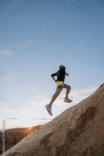 Male trail runner leaps and bounds up rocky incline, Utah photo