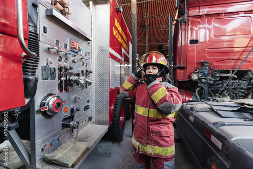 Female Firefighter In Fire Protection Suit standing at fire station photo