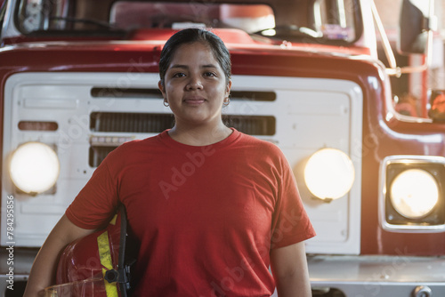 Portrait of smiling female firefighter standing at the fire station photo