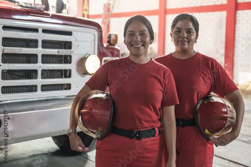 Portrait of happy female firefighters standing at fire station photo