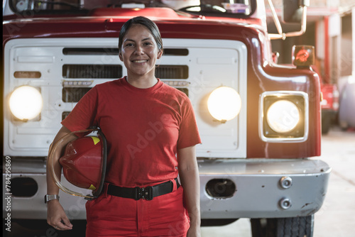 Portrait of smiling female firefighter standing at fire station photo