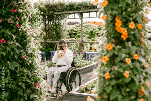 Teen female on wheelchair taking photos in garden photo