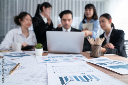 Focus financial data dashboard paper by business intelligence display graph  chart and statistic report on office table with blurred business people working in background. Habiliment