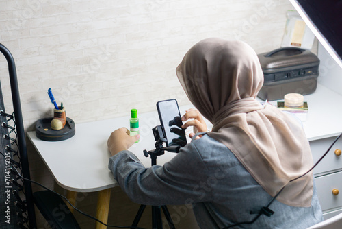 Woman with hijab is working with mobile phone to make a video and produce content for selling product