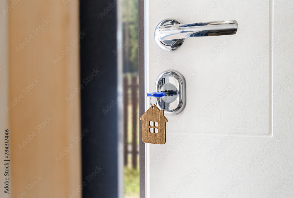 a key with a keychain in the shape of a house is inserted into the door lock