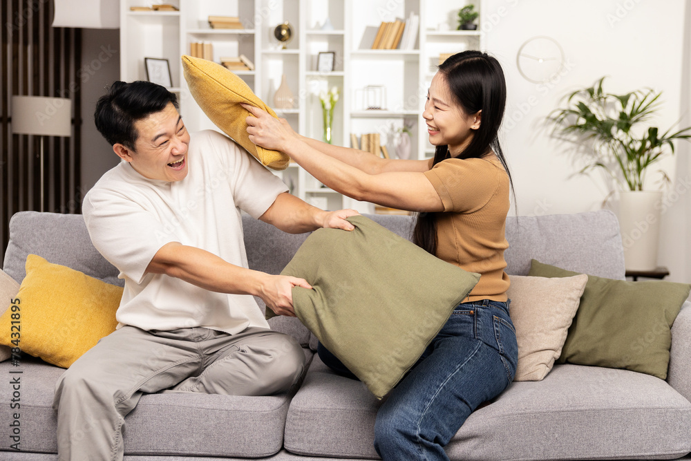 A joyful couple engaging in a playful pillow fight in their cozy living room, radiating happiness and love. A joyful couple engaging in a playful pillow fight in their cozy living room, radiating happiness and love.