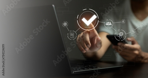 A person is pointing at a laptop screen with a check mark on it