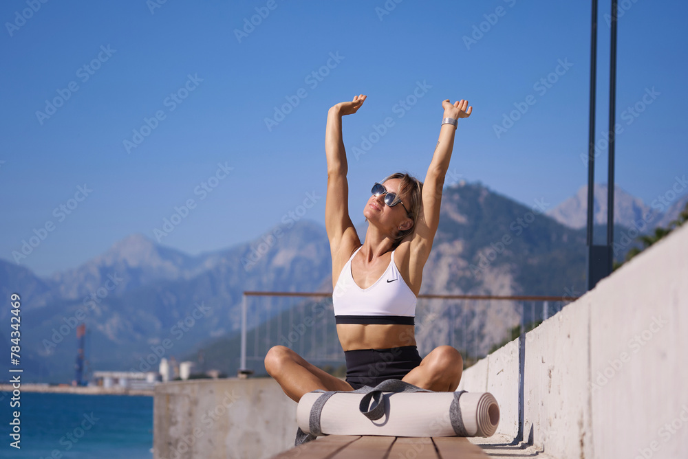 Portrait of caucasian young woman in sporty outfit relaxing meditating feeling zen-like on fitness mat in public park outdoors. Healthy active lifestyle. High quality photo Portrait of caucasian young woman in sporty outfit relaxing meditating feeling zen-like on fitness mat in public park outdoors. Healthy active lifestyle. High quality photo