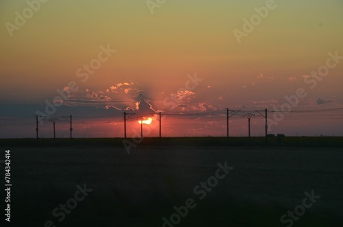 Beautiful scene of the silhouette of the powerlines with an orange sky at sunset