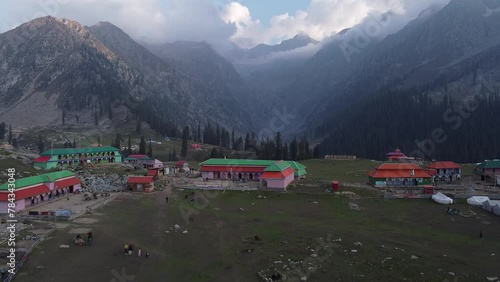 Drone flying over hikers and buildings in lush green valley in Jahaz Banda, Pakistan photo