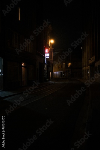 Narrow street surrounded by buildings in night © Wirestock