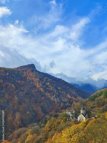 Drone vertical shot of a mountain church under blue cloudy sky © Wirestock