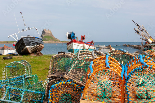 Lindisfarne, Holy Island, Northumberland, UK: the castle and harbour from the Common, with traditional old fishing boats and lobster pots in the foreground.