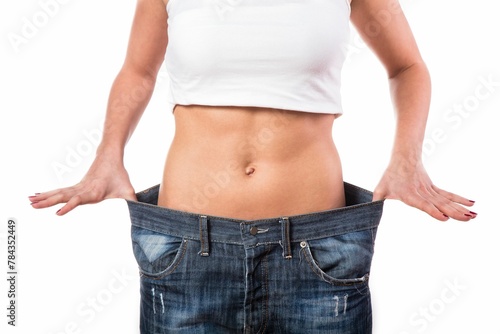 Fit girl stretching her jeans, demonstrating a large gap around her hips after weight loss © Wirestock