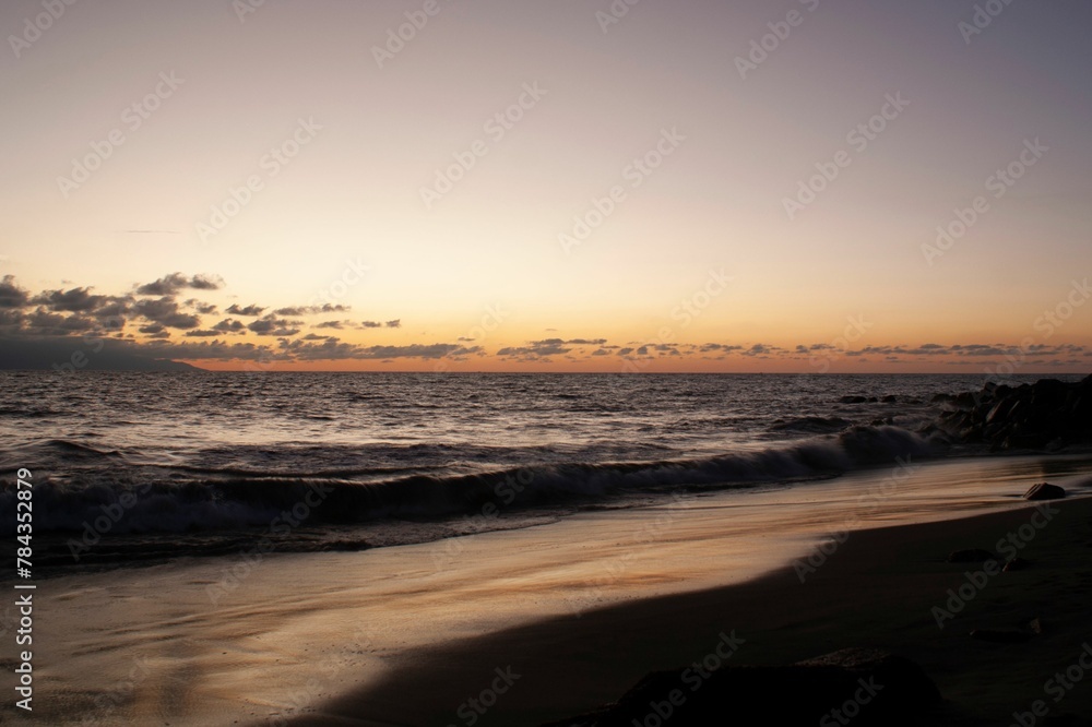 Sunset view over a seascape with clear sky and sun in the background stones silhouettes around