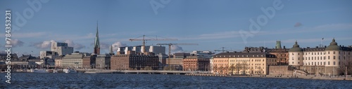 Panorama down town view old 1700s court houses, hotels, skyscrapers and Town City Hall pier with commuting steam boats a sunny spring evening in Stockholm