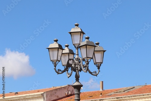 Pole with street lamps against a cloudy blue sky