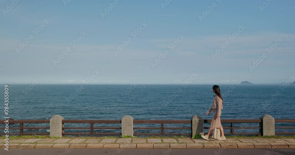 Woman walk along the waterfront with the blue sea in north coast in Taipei Woman walk along the waterfront with the blue sea in north coast in Taipei