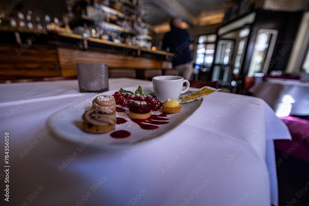 Set of cookies with berries and a cup of tea on a white plate in a cafe