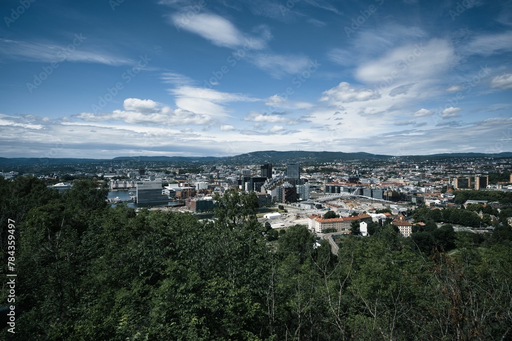 Cityscape of Oslo surrounded by greenery under a blue cloudy sky in Norway