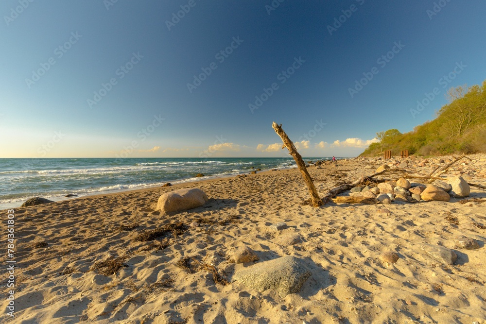 Closeup of rocks on a sandy beach with a sea and a blue sky in the background Closeup of rocks on a sandy beach with a sea and a blue sky in the background