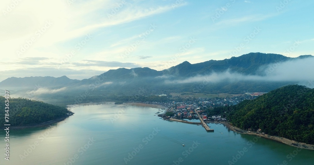 Aerial view of a calm coast, island, and village on a foggy day
