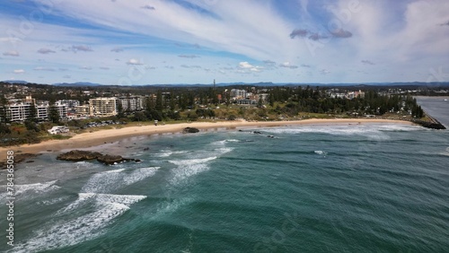 View of Town Beach in Port Macquarie, NSW, with green trees and buildings on sandy and rocky coast