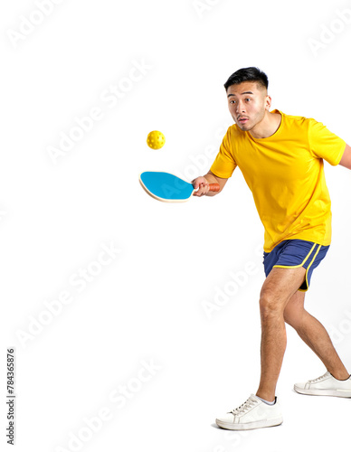 young oriental man in yellow and blue sportswear playing pickleball on white background