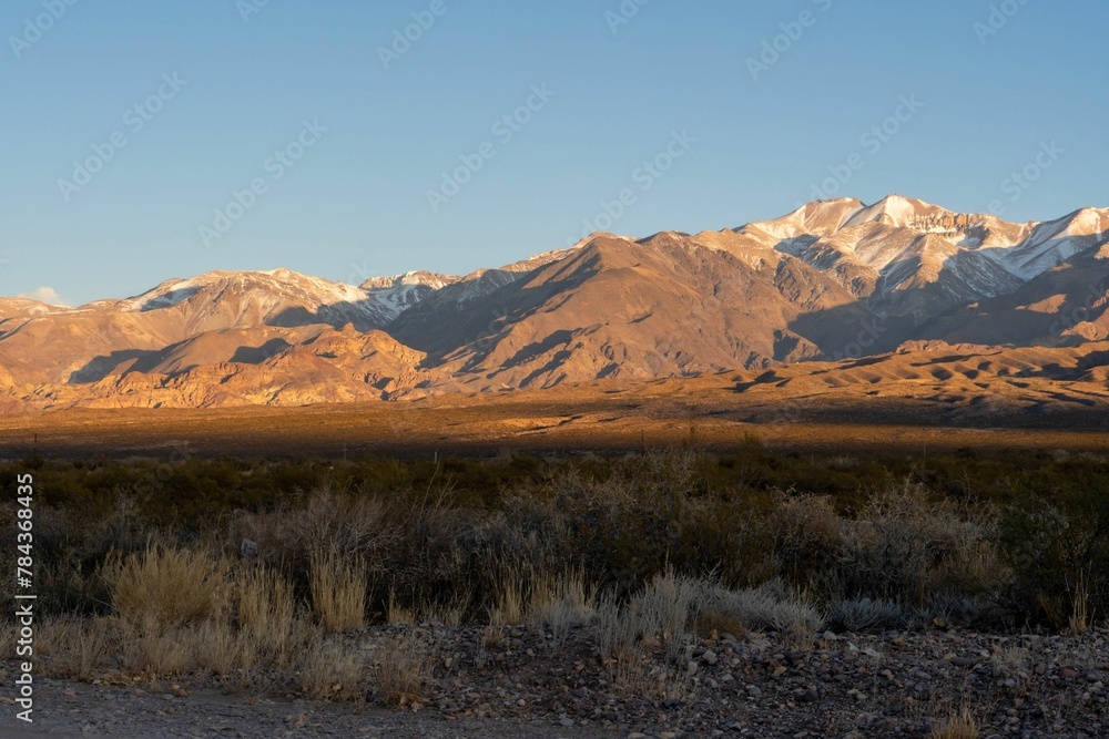 Scenic view of rocky mountain range and wide plain with wild grass on a sunny day Scenic view of rocky mountain range and wide plain with wild grass on a sunny day