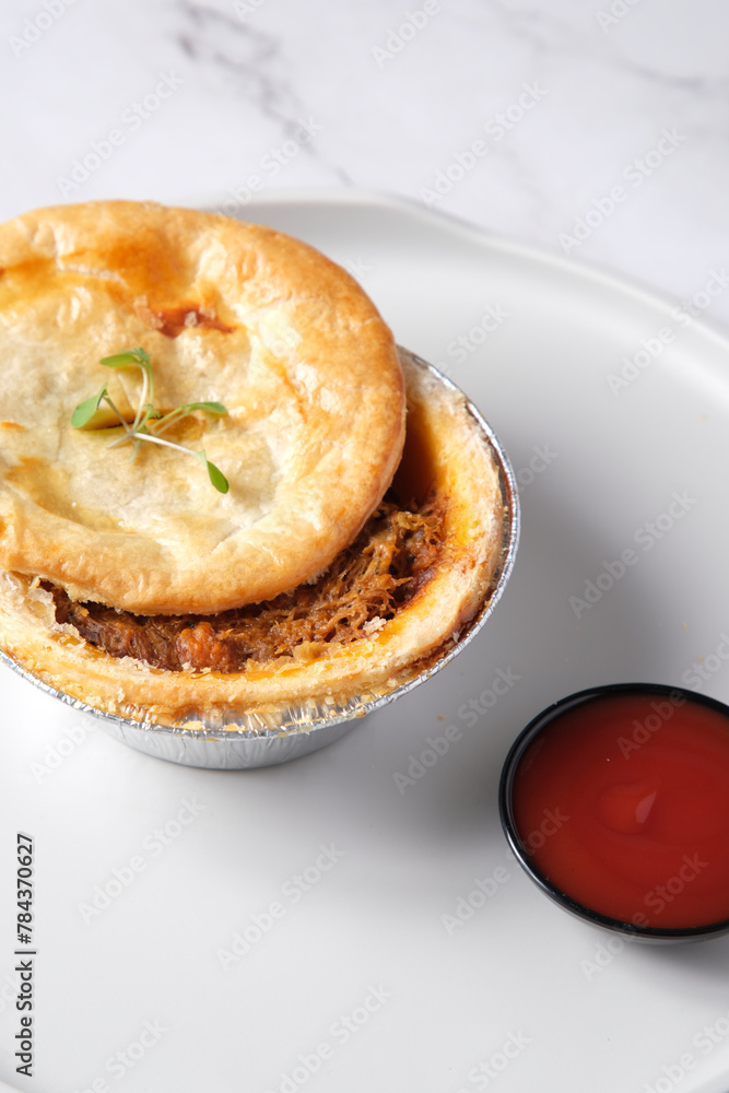 Small open meat pie with side of tomato sauce Small open meat pie with side of tomato sauce