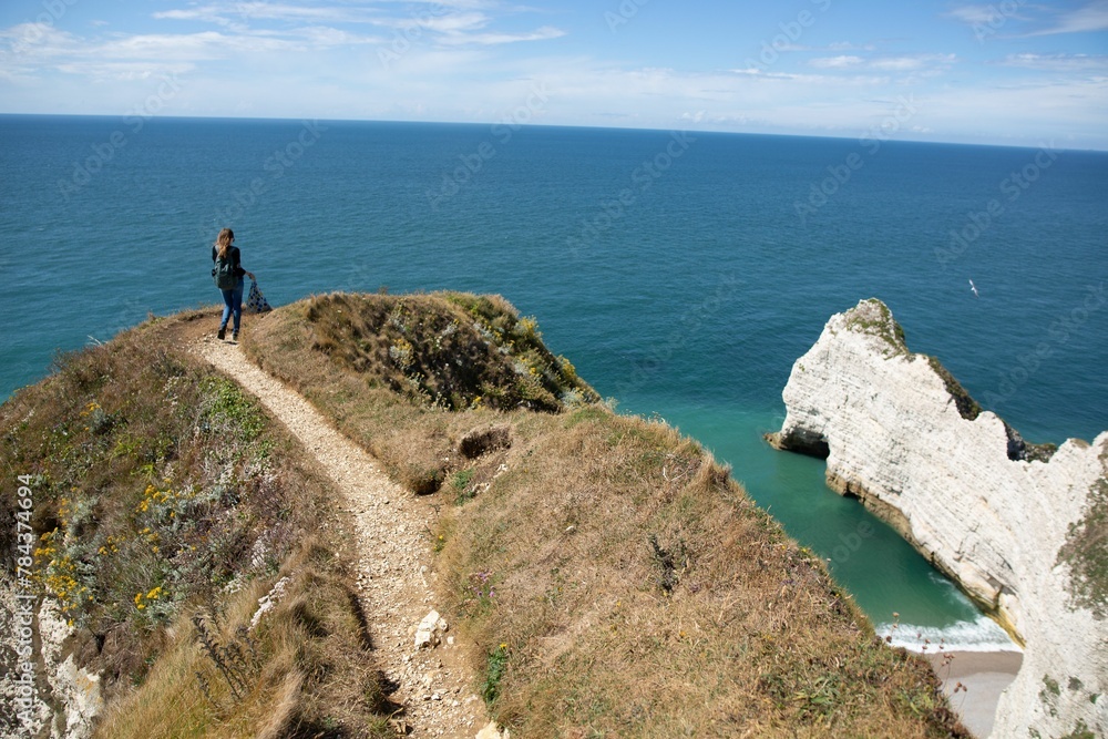 Woman walking on a trail on a clifftop with a seascape in the background, Etretat, France
