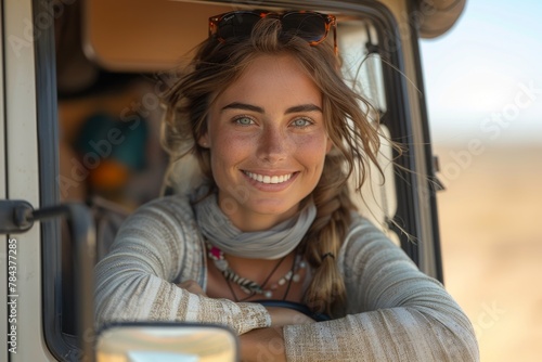 A beaming woman with sunglasses rests her arms on the edge of a van, reflecting a sense of adventure