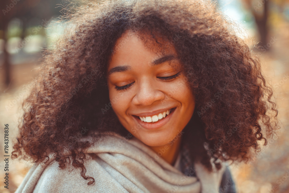 Cute autumn portrait of young happy curly african american woman enjoying fall season in park Cute autumn portrait of young happy curly african american woman enjoying fall season in park