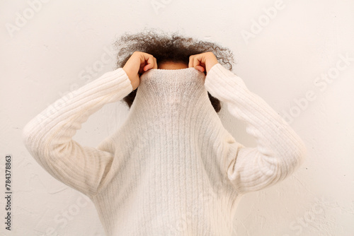 Tableau sur toile Curly african woman covering face with sweater collar, female taking off polo ne