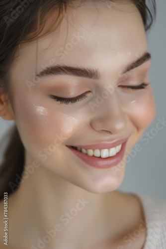 A close-up shot of a woman smiling with her eyes closed. Perfect for advertising and beauty campaigns