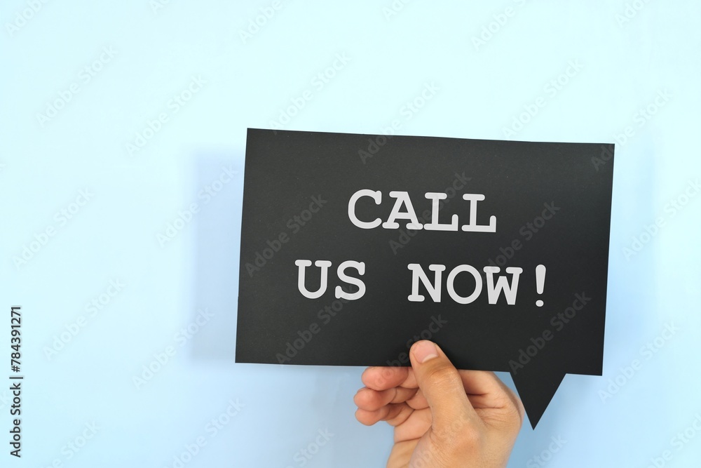 Human hand holding speech bubble with written phrase Call Us Now. Human hand holding speech bubble with written phrase Call Us Now.